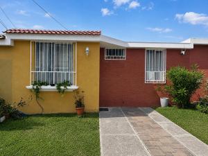 a yellow and red house with a green yard at Casa cómoda en zona residencial Ideal para familias y grupos in Villa Nueva