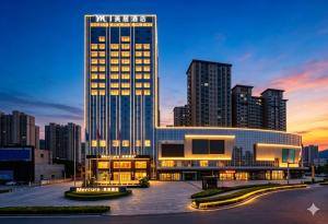 a lit up building with a city skyline in the background at Mercure Tianshui Downtown in Tianshui