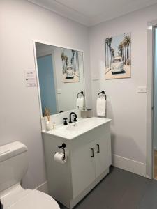a bathroom with a sink and a toilet and a mirror at Sussex View - Waterfront Couples Retreat in Sussex Inlet in Sussex Inlet +15 photos