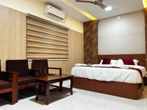 a bedroom with a bed and a table and a chair at S Hotel Neela in Musiri