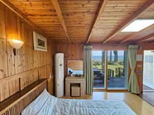 a bedroom with wooden walls and a bed and a refrigerator at Long Beach Pension in Seogwipo