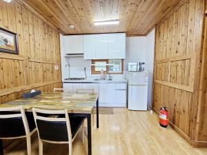 a kitchen with wooden walls and a table and chairs at Long Beach Pension in Seogwipo