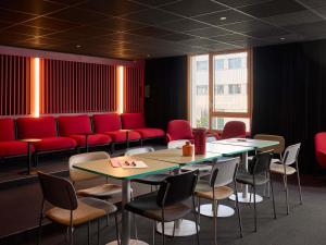 a waiting room with tables and chairs and red booths at You Hotel Amiens - Handwritten Collection in Amiens