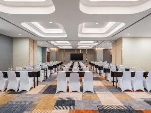 a conference room with tables and chairs and a screen at Novotel Jakarta Pulo Mas in Jakarta +100 photos