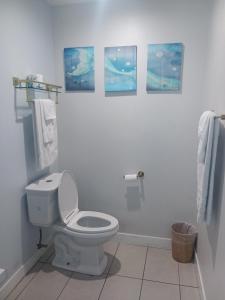 a bathroom with a toilet and pictures on the wall at Cali inn in Anaheim
