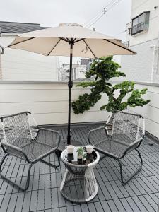 two chairs and an umbrella on a patio at 愉楽の宿 一棟貸切Villa in Osaka