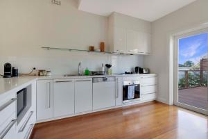 a white kitchen with white cabinets and a wooden floor at Barkly Cottage Bendigo in Bendigo