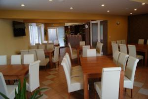 a restaurant with wooden tables and white chairs at Penzión Koruna in Nitrianske Rudno