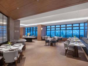 a restaurant with tables and chairs and large windows at NOVOTEL Zhoushan Luting in Zhoushan