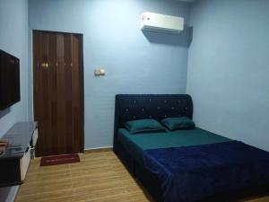 a blue room with a bed and a television at D'Biru Guest Room in Melur