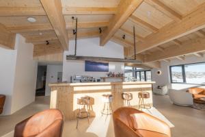 an open kitchen with wooden ceilings and a bar with stools at Carruthers Chalet in Perisher Valley