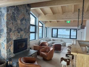 a living room with a fireplace and a stone wall at Carruthers Chalet in Perisher Valley