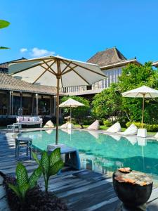 a swimming pool with an umbrella and chairs and tables at Spaces Bali Unique Boutique Hotel in Canggu +30 photos