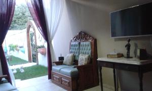 a room with a chair and a desk and a television at Pousada Jesmar in Praia do Frances