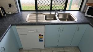 a kitchen counter with a sink and a dishwasher at The Goose Ponds in North Mackay