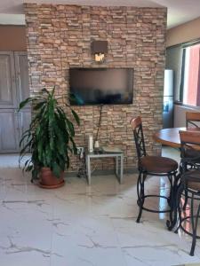 a living room with a stone wall with a flat screen tv at Towers by the Beach in Ocho Rios
