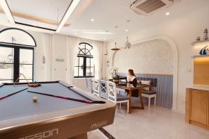 a woman sitting at a desk with a pool table at KB Villas 51 in Bình Tú