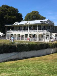 a large white house with people on the balcony at Truffle Ridge Vineyard Stay in Martinborough