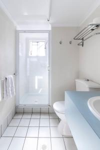 a white bathroom with a shower and a toilet at The Sunset Sea in Eimeo +2 photos