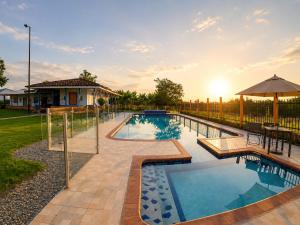 a swimming pool with a patio and an umbrella at Finca Hotel Estrella del Eden in Armenia