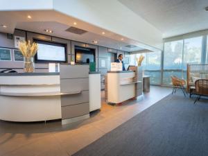 a man standing at a counter in a lobby at Novotel Poissy Orgeval in Orgeval +125 photos
