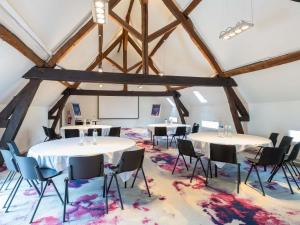 a room with tables and chairs in a room with beams at Novotel Saclay in Saclay +231 photos