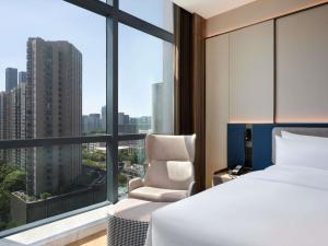 a bedroom with a bed and a chair and a large window at Novotel Hangzhou Binjiang in Hangzhou +84 photos