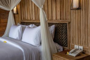 a bedroom with a bed with a phone on a table at DITUJU Ubud by GenuineHost in Ubud +35 photos