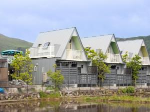a row of houses next to a body of water at Yufuin Onsen 8A1 Yaeichi in Yufu