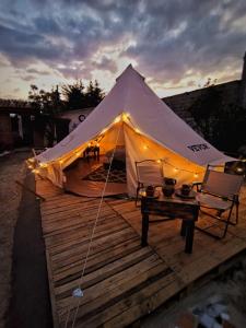 a tent on a wooden deck with two chairs and a table at Chantli Nawi Glamping & Temazcal in Ixtafiayuca