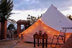 a tent with a table and a chair on a deck at Chantli Nawi Glamping & Temazcal in Ixtafiayuca