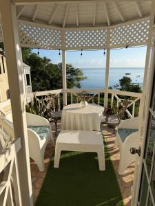 a table and chairs on a porch with the ocean at One more night in Ocho Rios