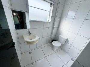 a white bathroom with a toilet and a sink at Hotel Divisa poá in Poá