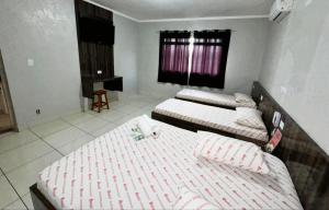 a bedroom with two beds and a table in it at Hotel Divisa poá in Poá +2 photos