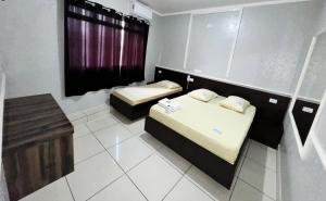 two beds in a small room with a window at Hotel Divisa poá in Poá