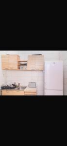 a kitchen with wooden cabinets and a white refrigerator at Brufut Residencies Apartment 5 in Brufut