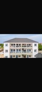 a large white apartment building with a black roof at Brufut Residencies Apartment 5 in Brufut