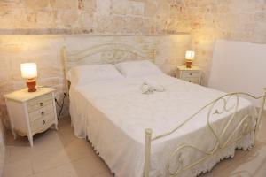 アルベロベッロにあるCasa dell'ulivo - Relax Lumieri - a due passi dal centro Alberobelloのベッドルーム1室(白いベッド1台、ナイトスタンド2台付)