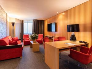 a hotel room with red chairs and a table at Novotel Valence Sud in Valence