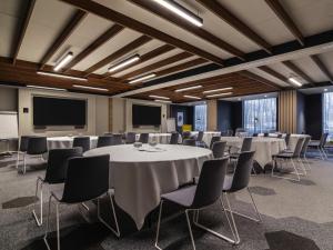 a conference room with tables and chairs and a projection screen at Novotel Amsterdam City in Amsterdam