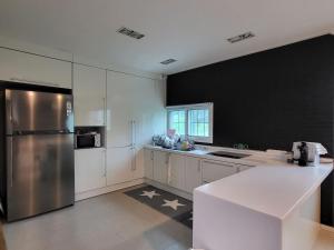 a kitchen with white cabinets and a stainless steel refrigerator at Haepung Stay in Yŏnamp'o +10 photos