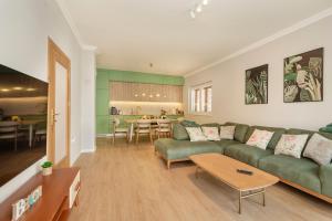 a living room with a green couch and a kitchen at House Olive Tree in Bijela