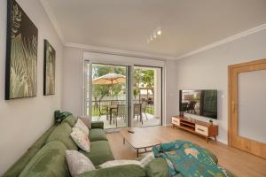 a living room with a green couch and a television at House Olive Tree in Bijela