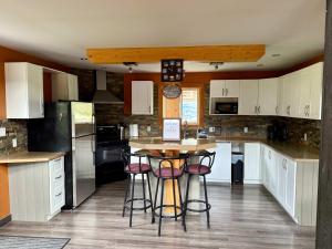 a kitchen with white cabinets and a island with bar stools at GROWL Lodge - Hot Tub & Mountain Views! in Golden