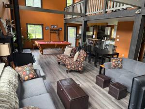a living room with couches and a pool table at GROWL Lodge - Hot Tub & Mountain Views! in Golden