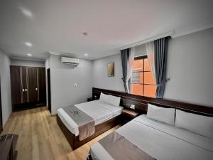 a hotel room with two beds and a window at HS Dobry Hotel Ha Long in Ha Long