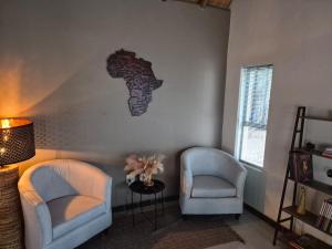 a living room with two chairs and a map on the wall at Switsongo B&B in Hoedspruit