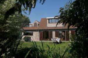 a brick house with a table and a chair in the yard at Au Grenier des Coccinelles in Pecq