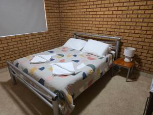 a bed in a room with a brick wall at Puggle Palace, 21A Bower Street in Jurien Bay
