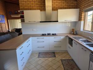 a kitchen with white cabinets and a sink at Puggle Palace, 21A Bower Street in Jurien Bay